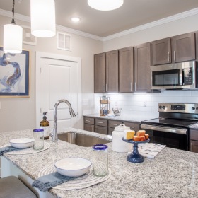 Kitchens outfitted with granite countertops Huntsville Apartments - Ariza Research - Kitchen with Granite Countertop Island, Wooden Cabinetry, and Stainless-Steel Appliances